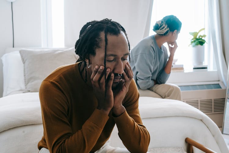 African American Couple Resting On Bed With Sad Face