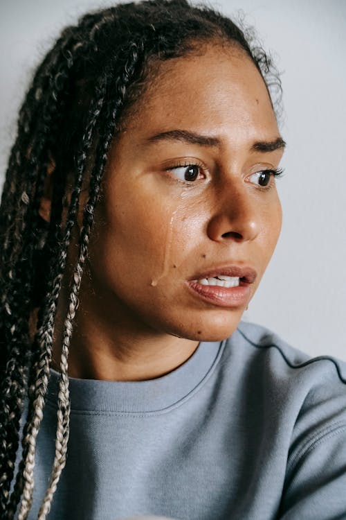 Free Young depressed African American female in casual outfit crying while looking away in daytime Stock Photo