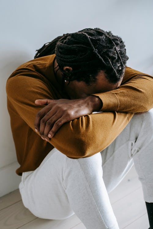 Free Unrecognizable upset ethnic man on floor at home Stock Photo