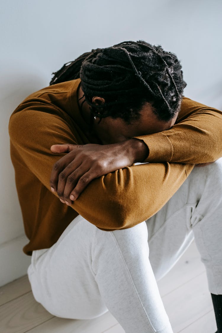 Unrecognizable Upset Ethnic Man On Floor At Home