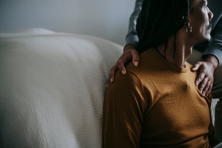 Crop Friend Reassuring Sad Black Man On Couch In House