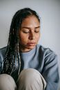 Sorrowful ethnic woman crying on light background