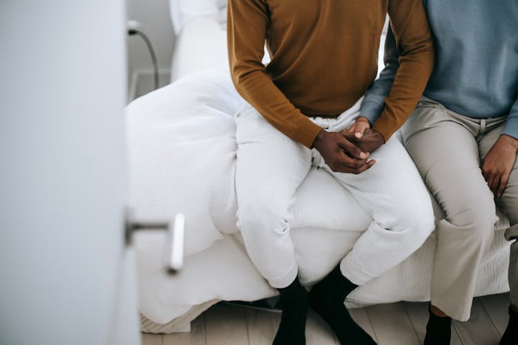 Crop Black Couple Holding Hands On Bed At Home