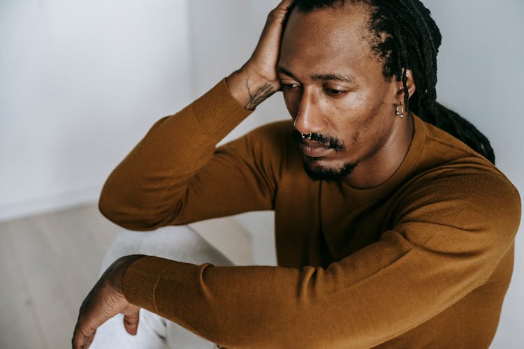 Crop Black Man With Mental Problem On Floor At Home