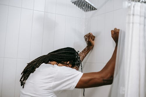Free Unrecognizable depressed black man under water flow in shower Stock Photo