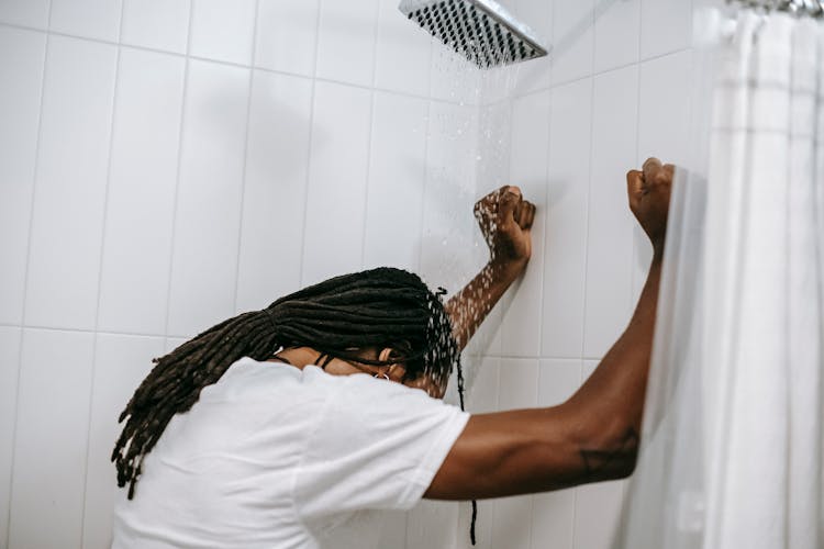 Unrecognizable Depressed Black Man Under Water Flow In Shower