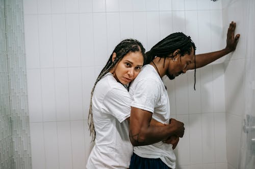 Sad black loving couple hugging in bathroom after argument