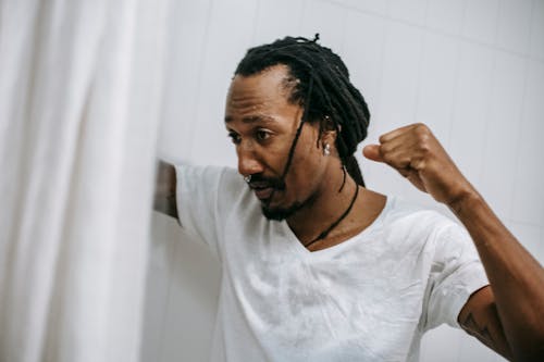 Free Aggressive young black man with raised fist in bathroom Stock Photo