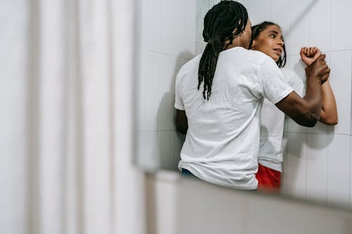 Free Anonymous black man pushing scared wife to wall during argument in bathroom Stock Photo