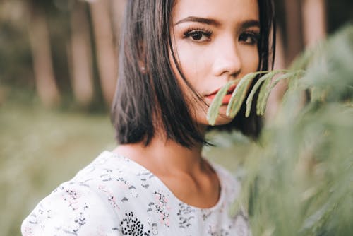 Attractive young woman near green tree