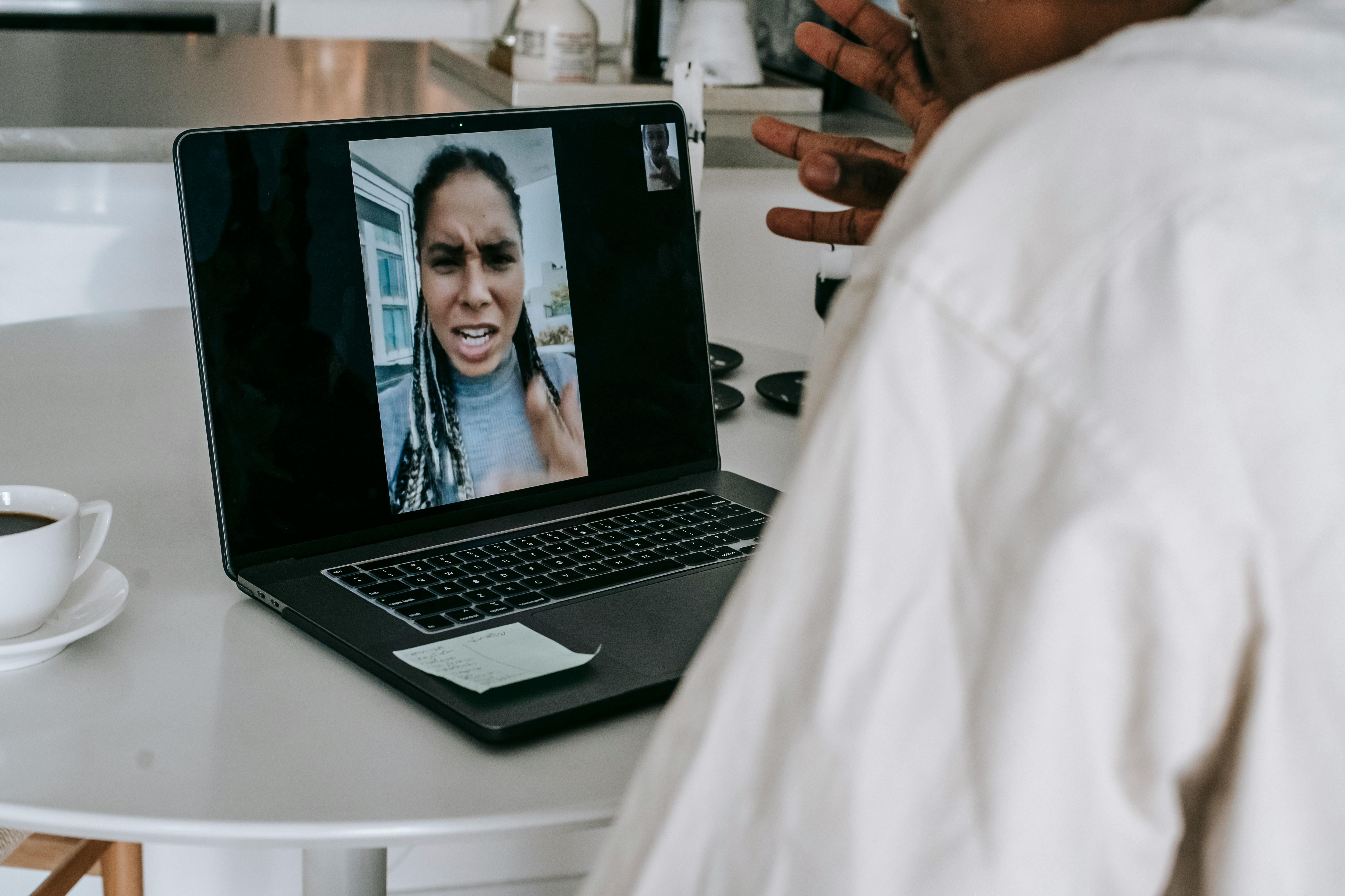 unrecognizable ethnic man having video conference with upset girlfriend
