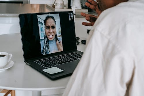 Unrecognizable ethnic man having video conference with upset girlfriend