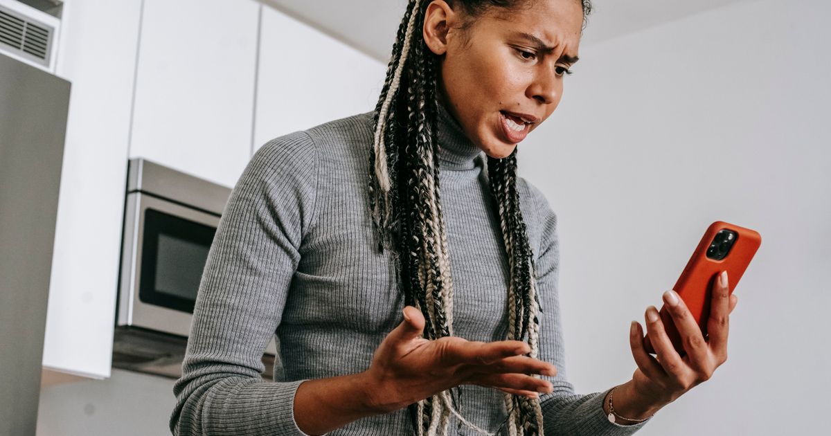 Frustrated person looking at a phone screen in a kitchen