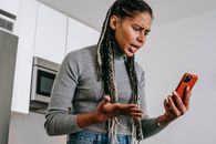 Annoyed black woman having video chat on smartphone at home