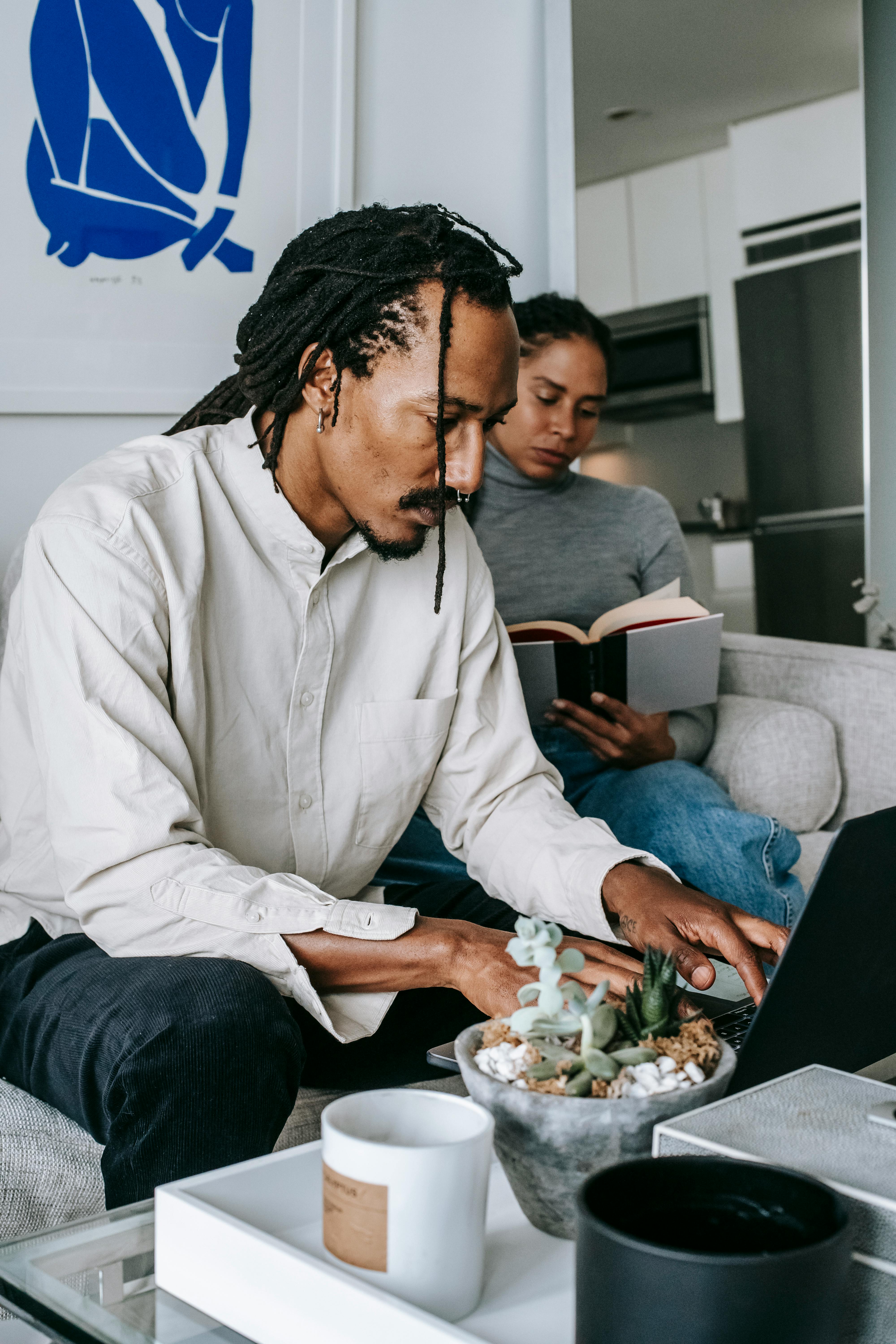 focused young black couple using netbook and reading book in living room