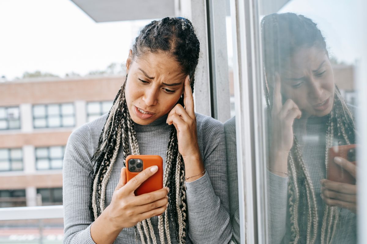 Mulher observando o celular com expressão de insatisfação