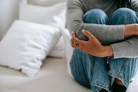 一位无脸的女性庄稼孤独地坐在床上，抱着膝盖，感到无助和沮丧