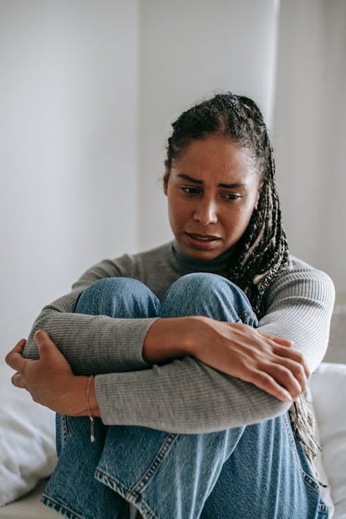 Free Upset ethnic woman embracing knees feeling frustrated Stock Photo