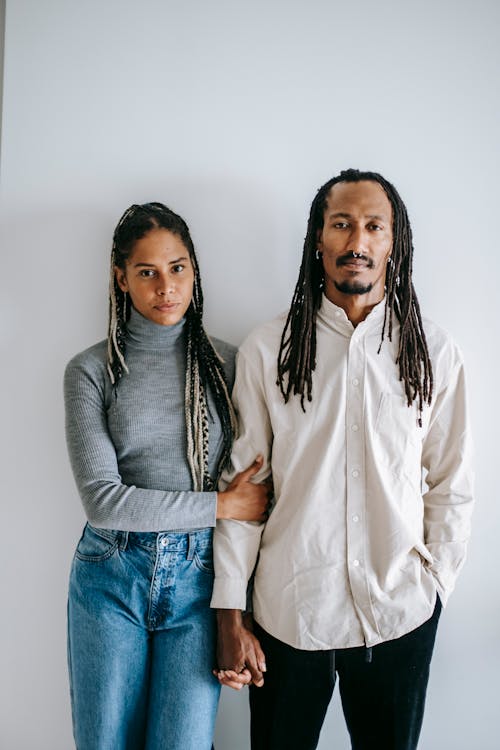 Free Serious ethnic couple holding hands in studio Stock Photo