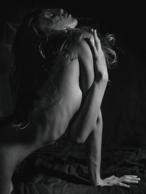 Sensual black and white portrait of a woman in an artistic studio pose.