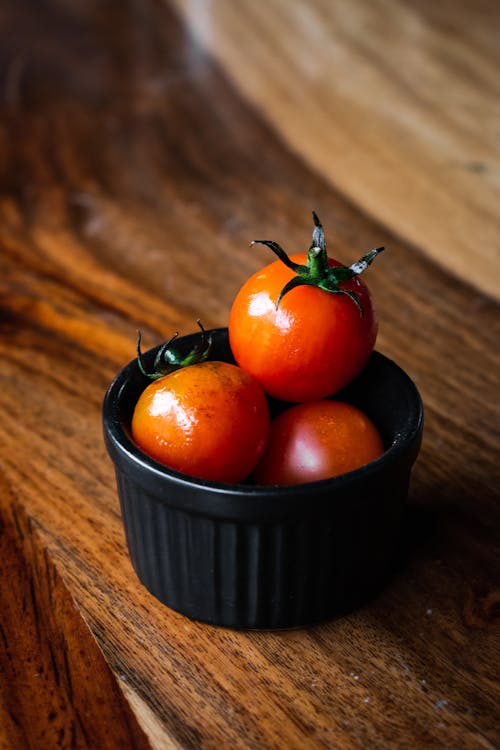 Close-up Shot of Orange Tomatoes on a Black Bowl