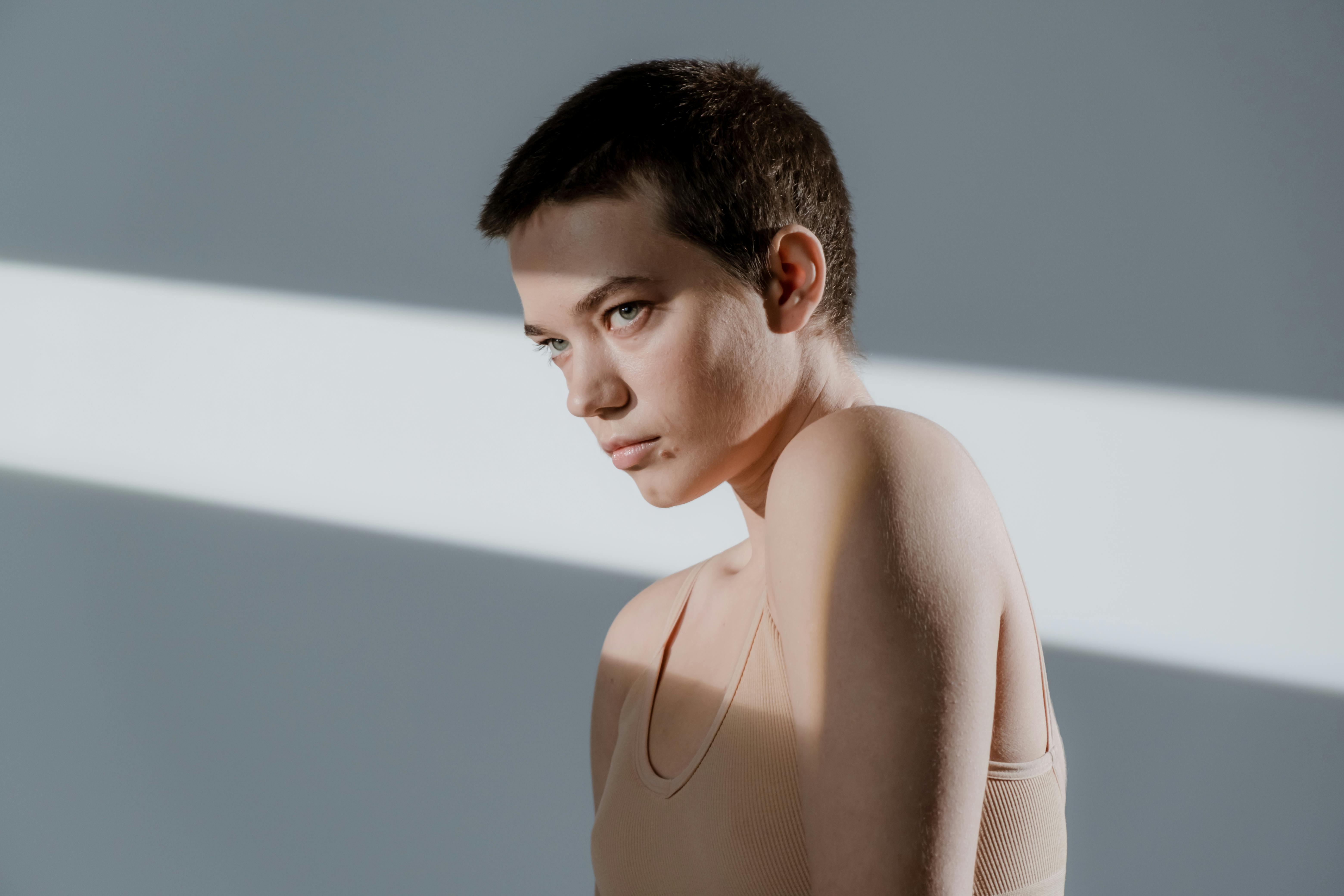 A Woman Wearing a Beige Sports Bra Using a Razor on Her Short Hair · Free  Stock Photo