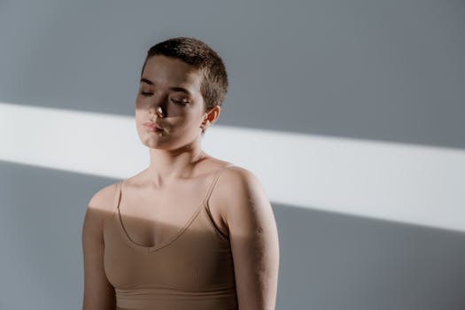 Studio portrait of a woman with short hair in a beige top and closed eyes, capturing serene expression.