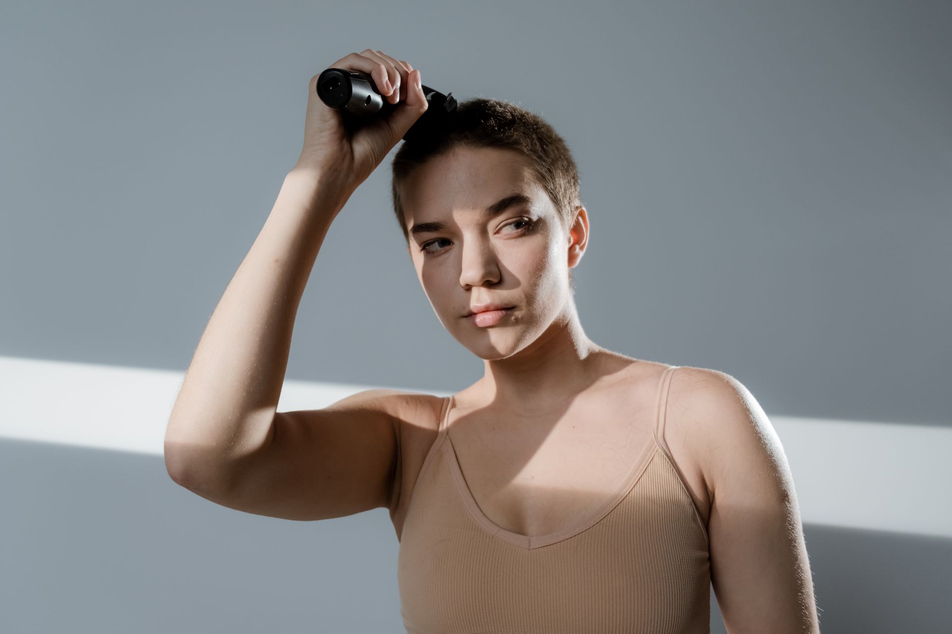 A Woman Trimming her Hair using Hair Clipper