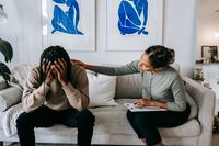 One partner comforting the other on a sofa