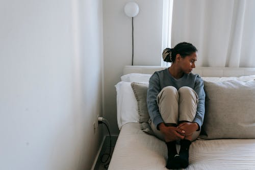 Sad black woman resting on bed at home