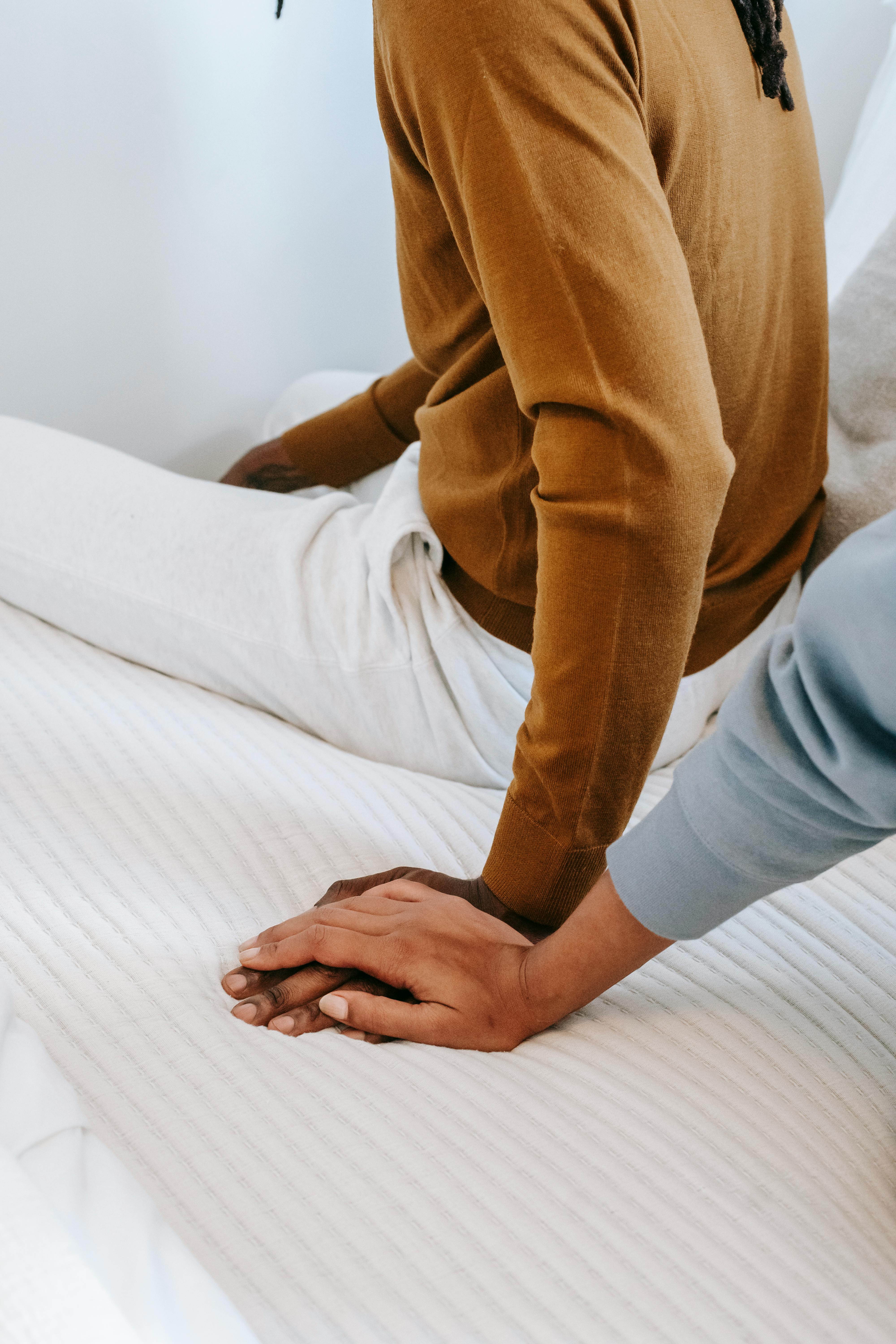 crop black woman touching hand of boyfriend on bed