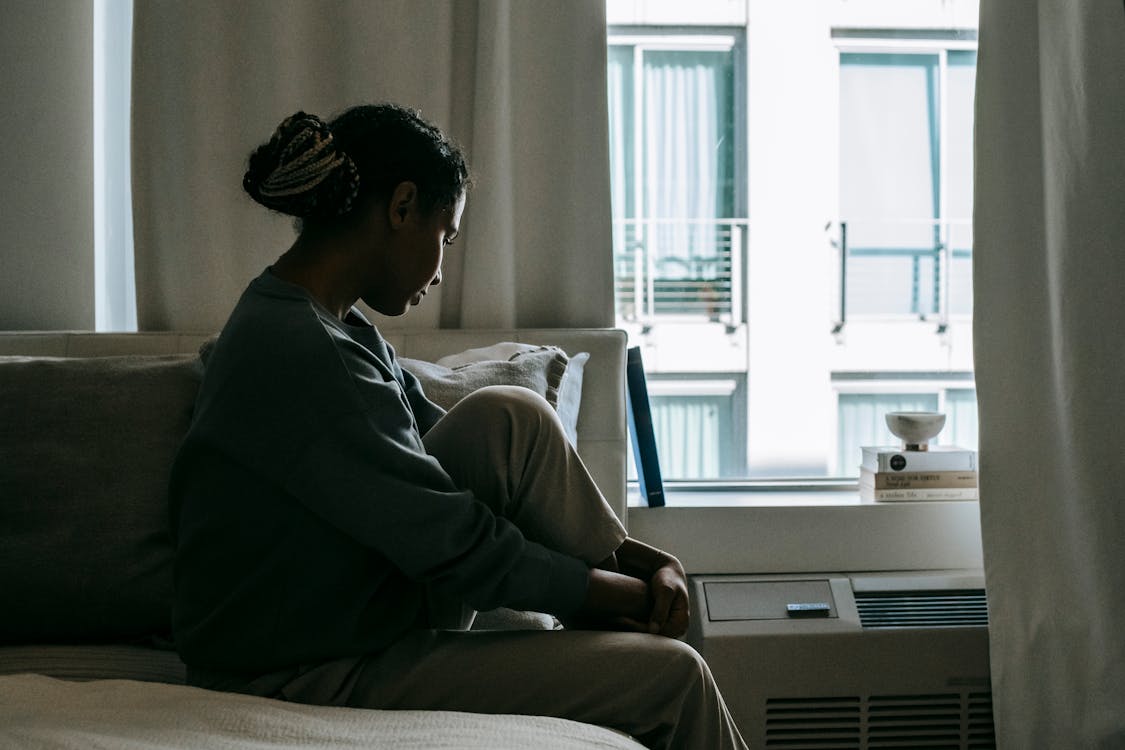 Upset black woman on bed in house