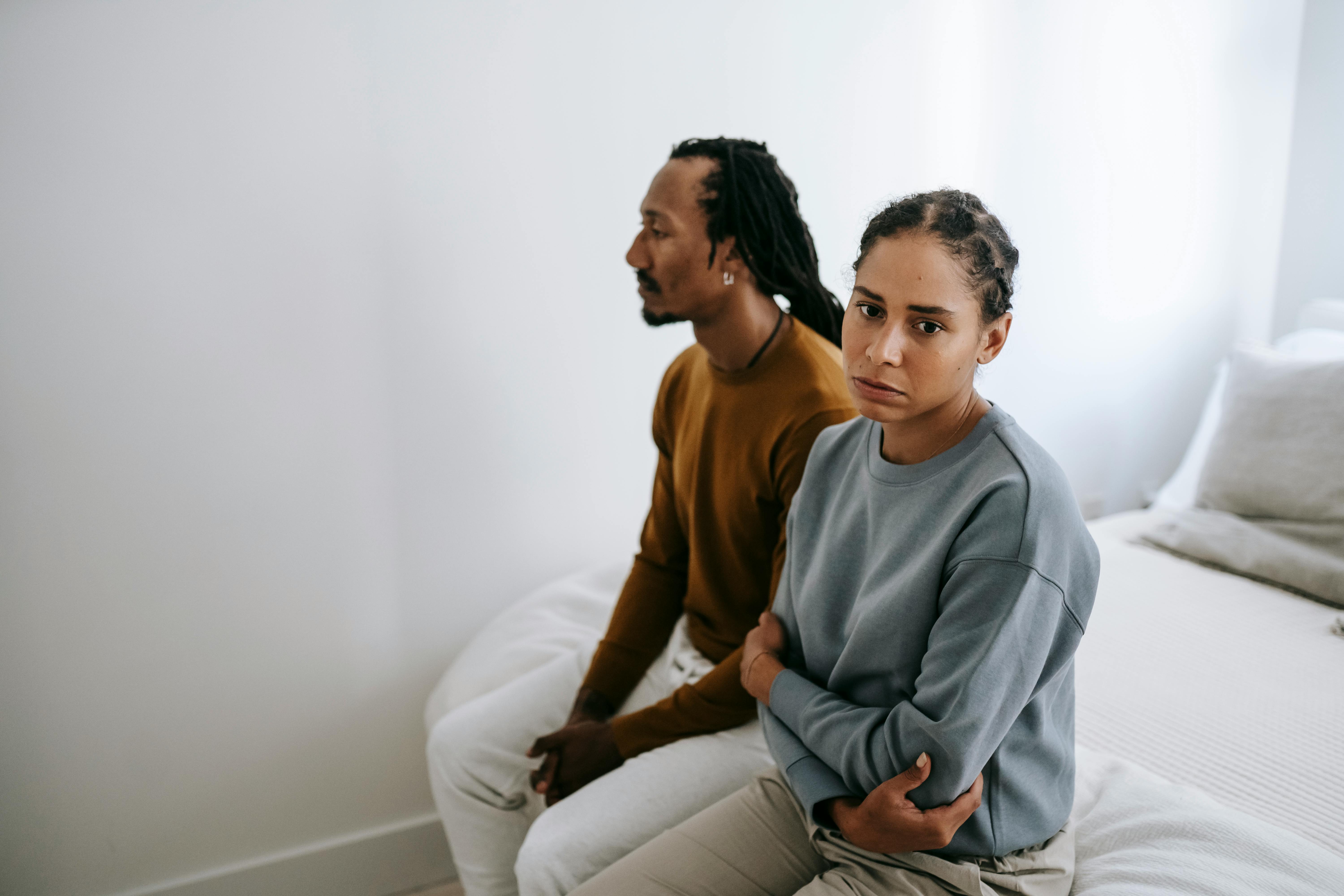 unhappy black couple sitting on bed together