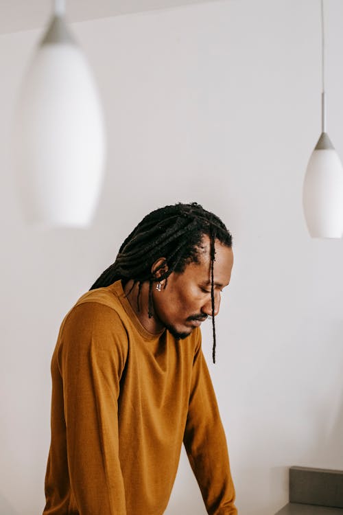 Sad black man standing with eyes closed in light room