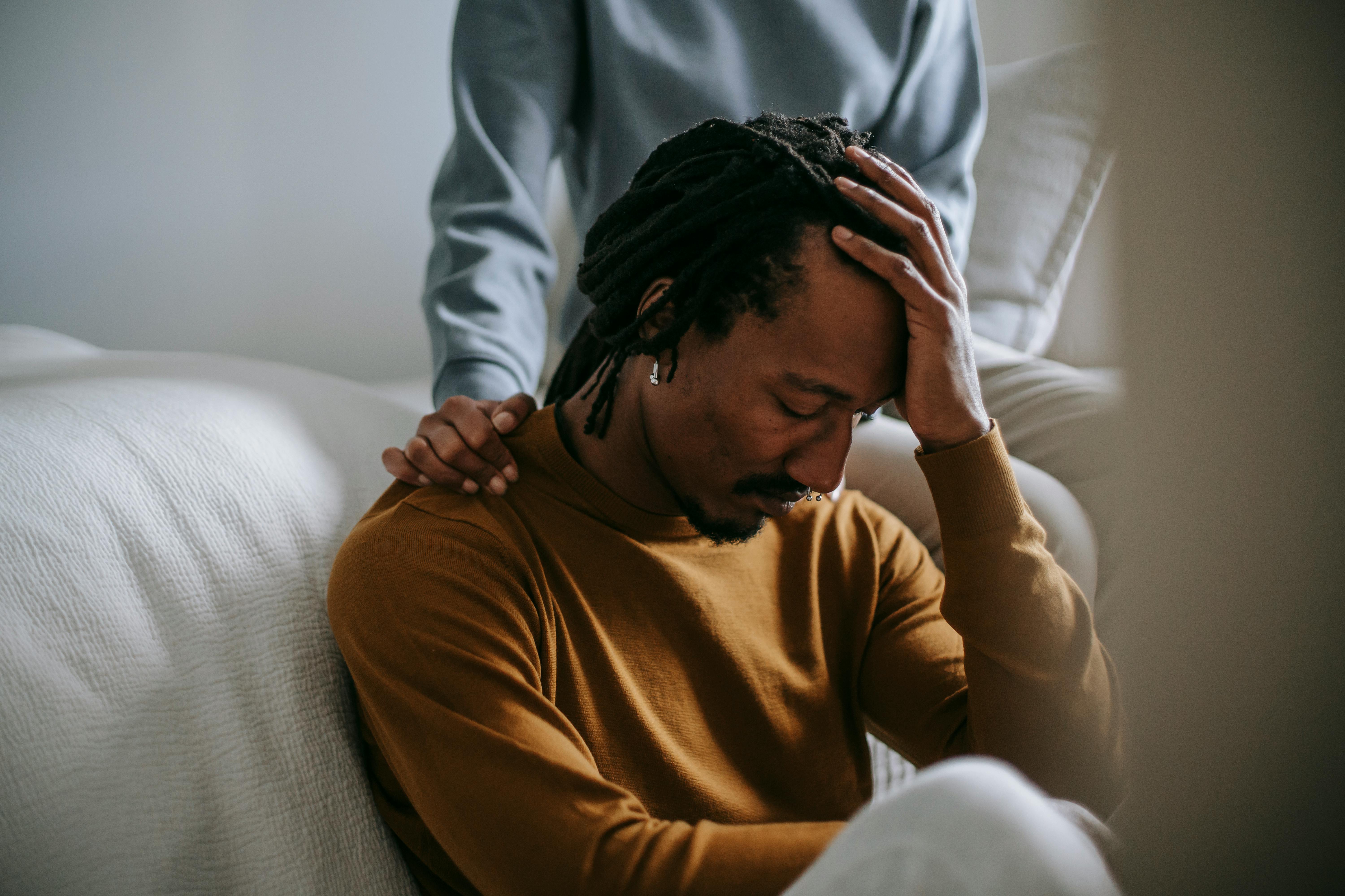 Sorrowful black man touching head in dismay near supporting wife · Free Stock Photo