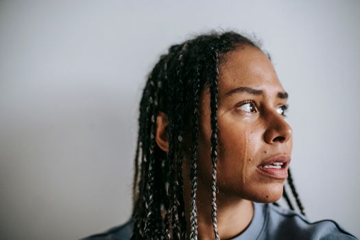 Mournful black woman crying in light room