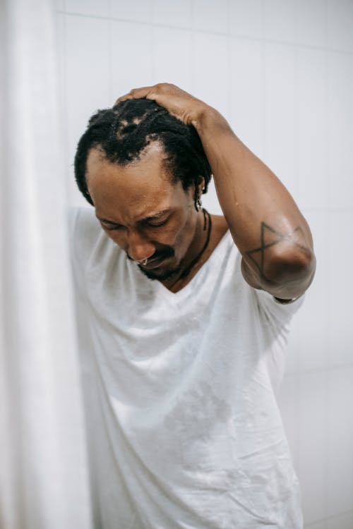 Free Unhappy black man touching head in shower Stock Photo