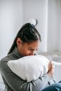Crying black woman hugging pillow in bedroom