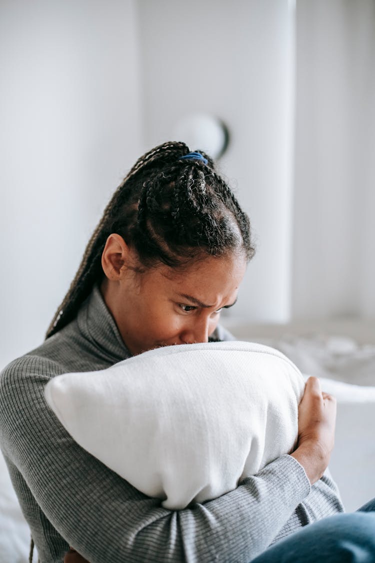 Crying Black Woman Hugging Pillow In Bedroom