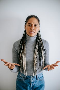 An adult black woman showing frustration and displeasure indoors with a gesture.