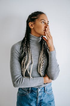 一名扎着辫子的女人在白色背景下摆出沉思的姿势