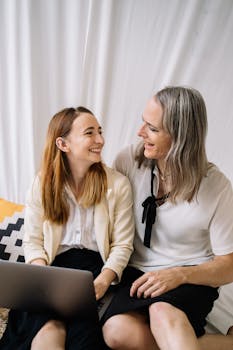 A cheerful couple sitting together indoors, working on a laptop and enjoying each other's company.