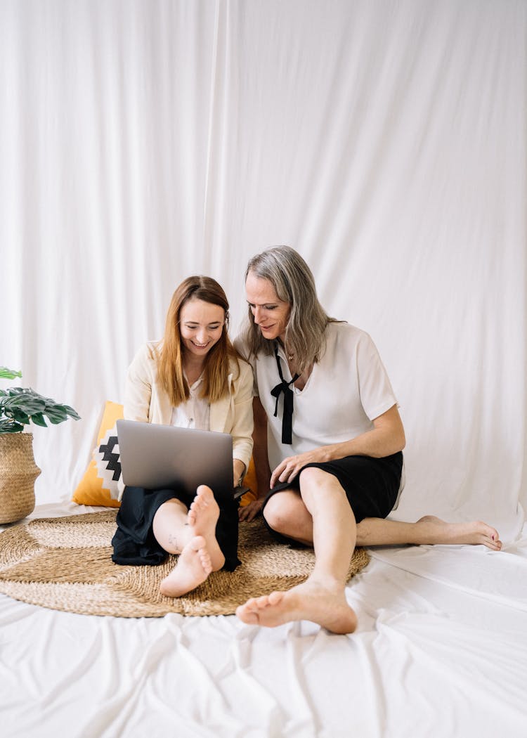 Couple Staring At A Laptop While Sitting On The Floor