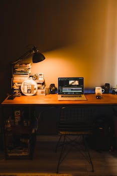 Warmly lit home office setup with a wooden desk, books, and a laptop. Perfect for productivity.