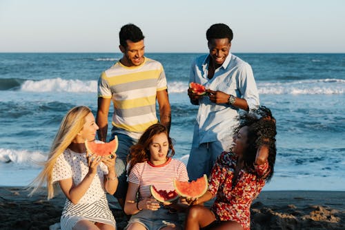 Free A Group of Friends Eating Watermelons Near the Sea Stock Photo