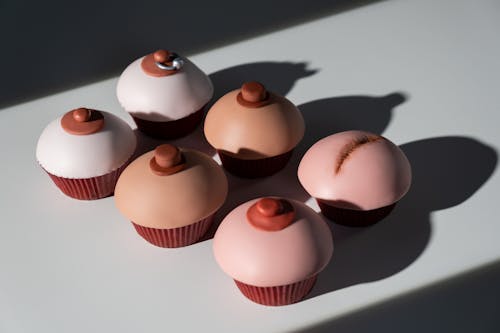 Creative cupcakes designed for breast cancer awareness in a flat lay composition highlighting diversity and support.