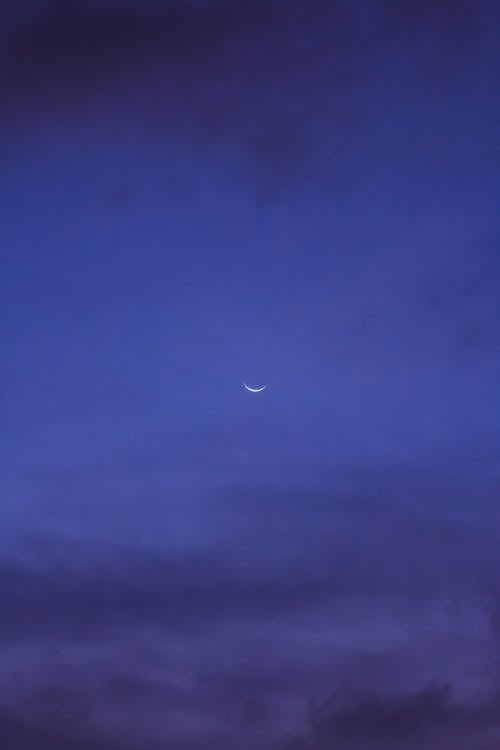 Free Dark clouds floating on blue sky with shining crescent moon in evening in nature Stock Photo