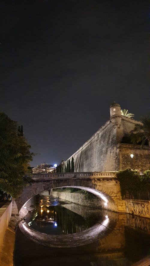 Stone Bridge and Fortification Wall over River in Palma on Mallorca in Spain at Night