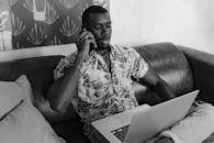 Man in White and Black Floral Button Up Shirt Sitting on Couch