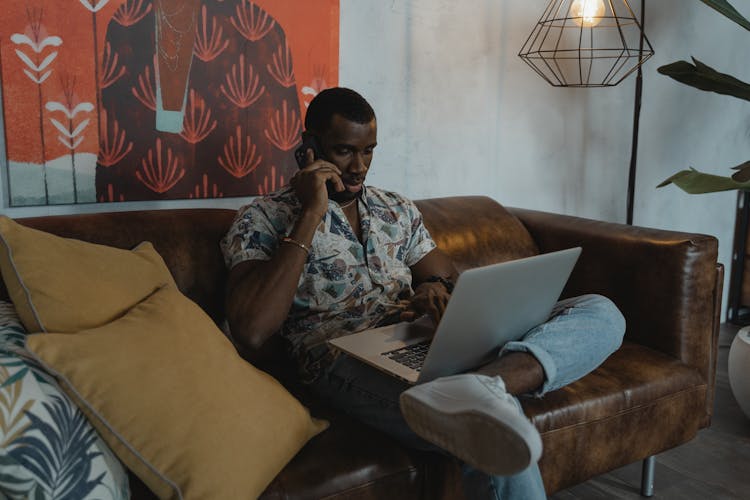 A Man Working From Home While Sitting On A Couch